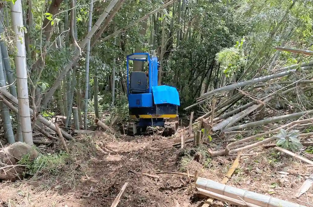 林業ヤマラボの青色のショベルカーが森林内で作業道を造っている様子